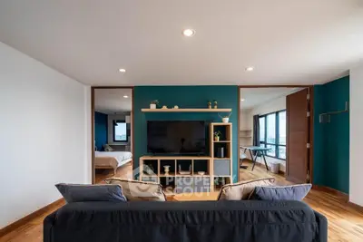 Modern living room with stylish decor and open layout, featuring a cozy bedroom view.
