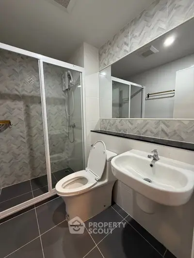 Modern bathroom with sleek design, featuring a glass shower enclosure and stylish tile work.