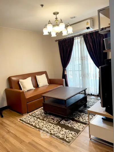 Cozy living room with elegant chandelier and leather sofa, featuring a stylish coffee table and floor-to-ceiling curtains.