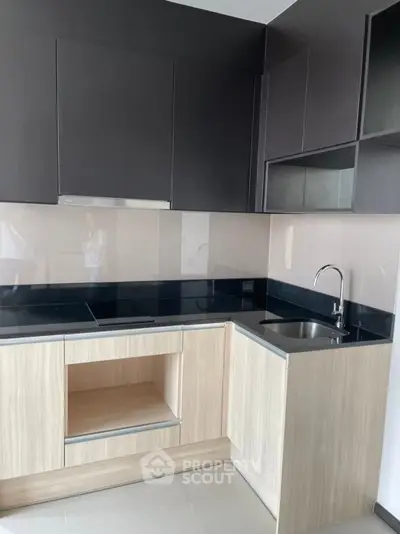 Modern kitchen with sleek cabinetry and black countertops in a stylish apartment.
