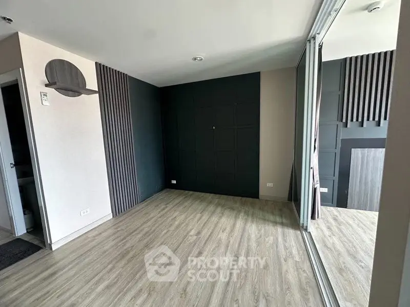 Spacious modern living room with sleek wood flooring and stylish wall accents.