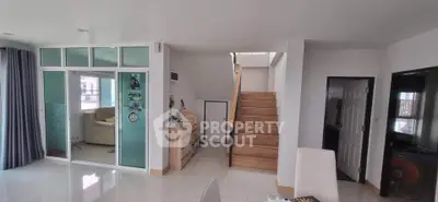 Spacious modern living area with staircase and glass partition, ideal for family gatherings.