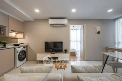 Modern living room with washing machine and open layout, featuring neutral tones and sleek design.