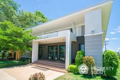 Modern building exterior with lush landscaping and clear blue sky.