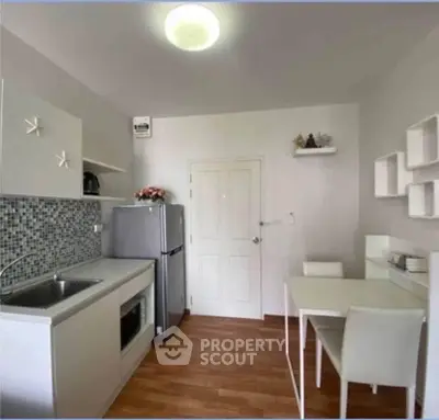 Modern kitchen with sleek white cabinets, mosaic backsplash, and compact dining area.