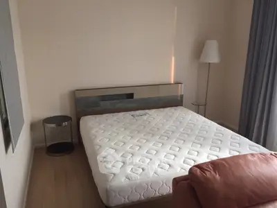 Spacious bedroom with a large bed, modern headboard, elegant floor lamp, and plush curtains, offering a serene and comfortable living space.