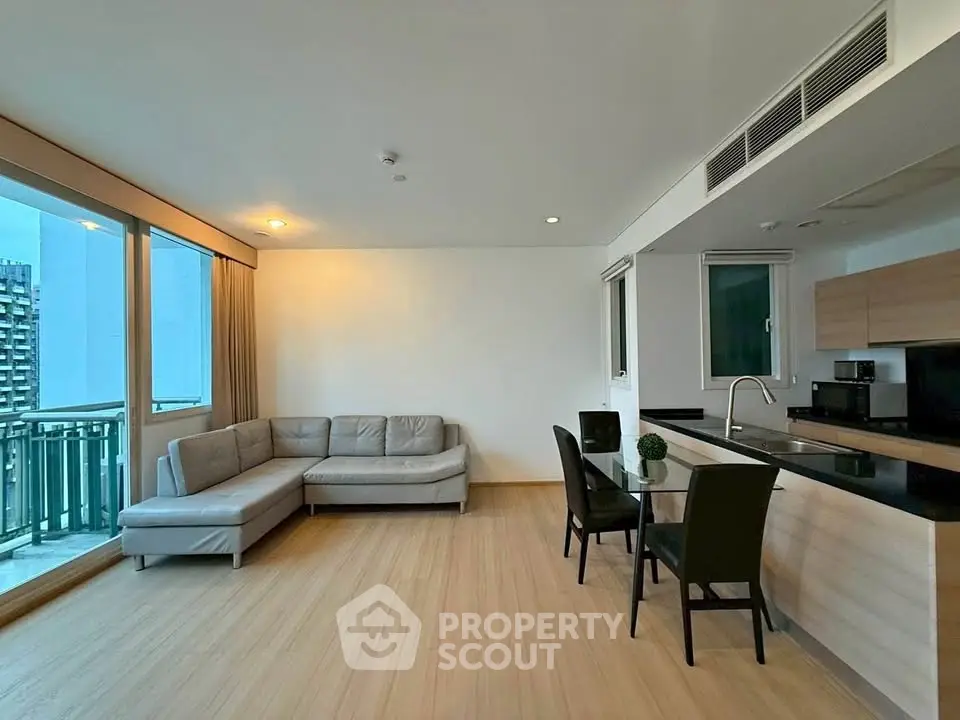 Modern open-plan living room with kitchen and balcony view