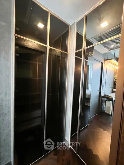 Modern apartment interior with sleek black glass wardrobes and elegant lighting