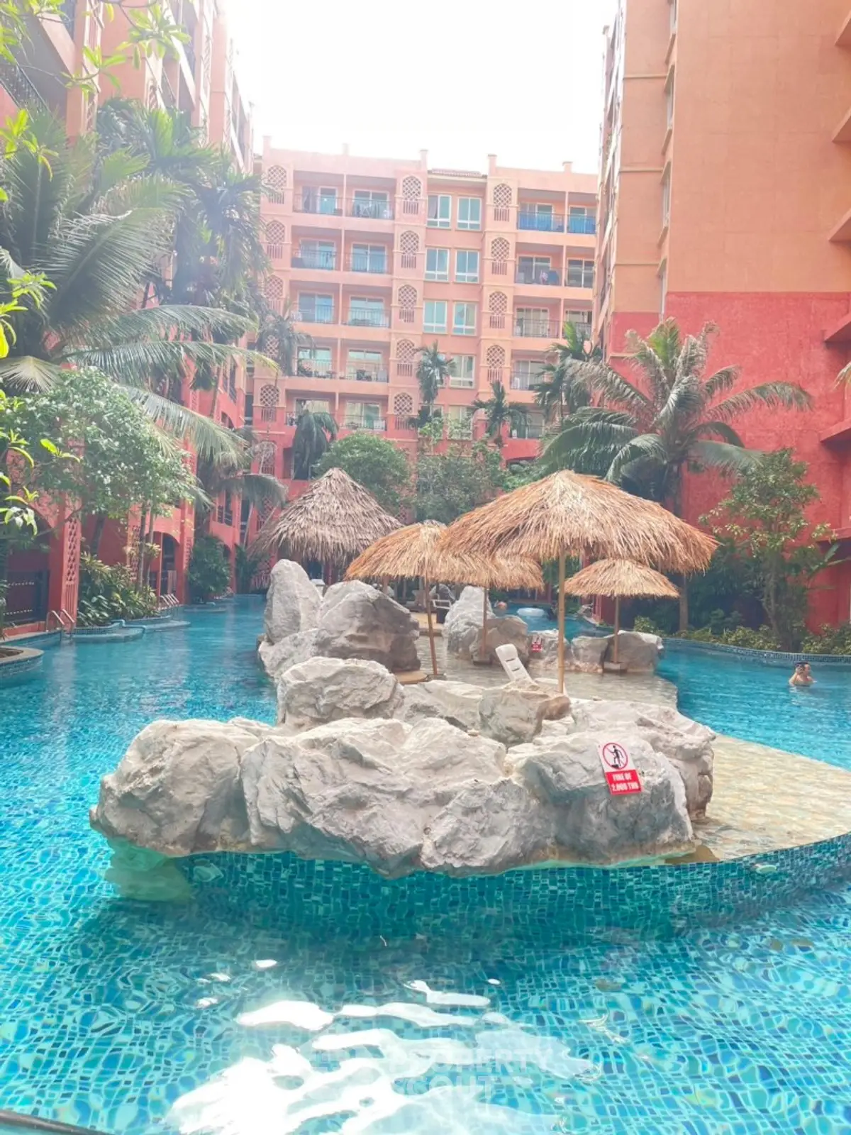 Luxurious resort-style pool with tropical landscaping and rock features in a vibrant residential complex.