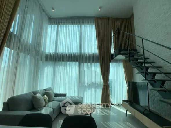 Spacious modern living room with high ceilings and stylish staircase.