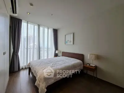 Spacious bedroom with large window and modern decor in high-rise apartment