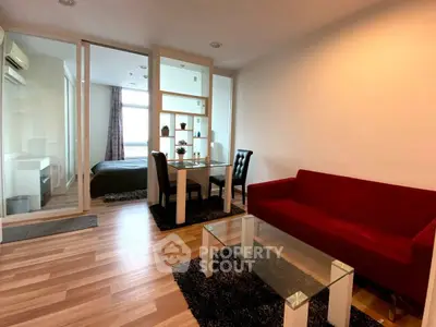 Modern apartment with open living and dining area, featuring sleek furniture and wooden flooring.