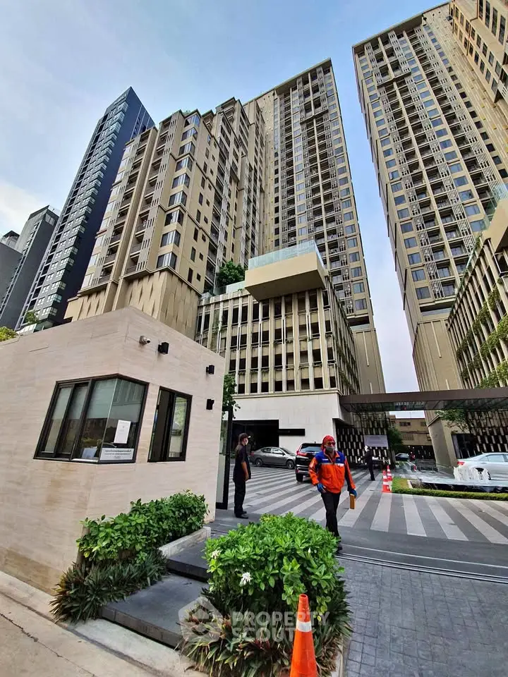 Modern high-rise residential building with security entrance and lush greenery.