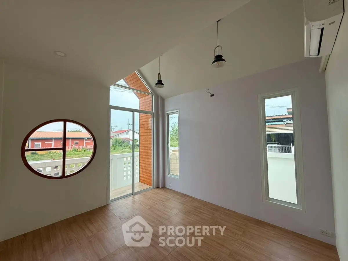Spacious modern room with unique circular window and balcony access
