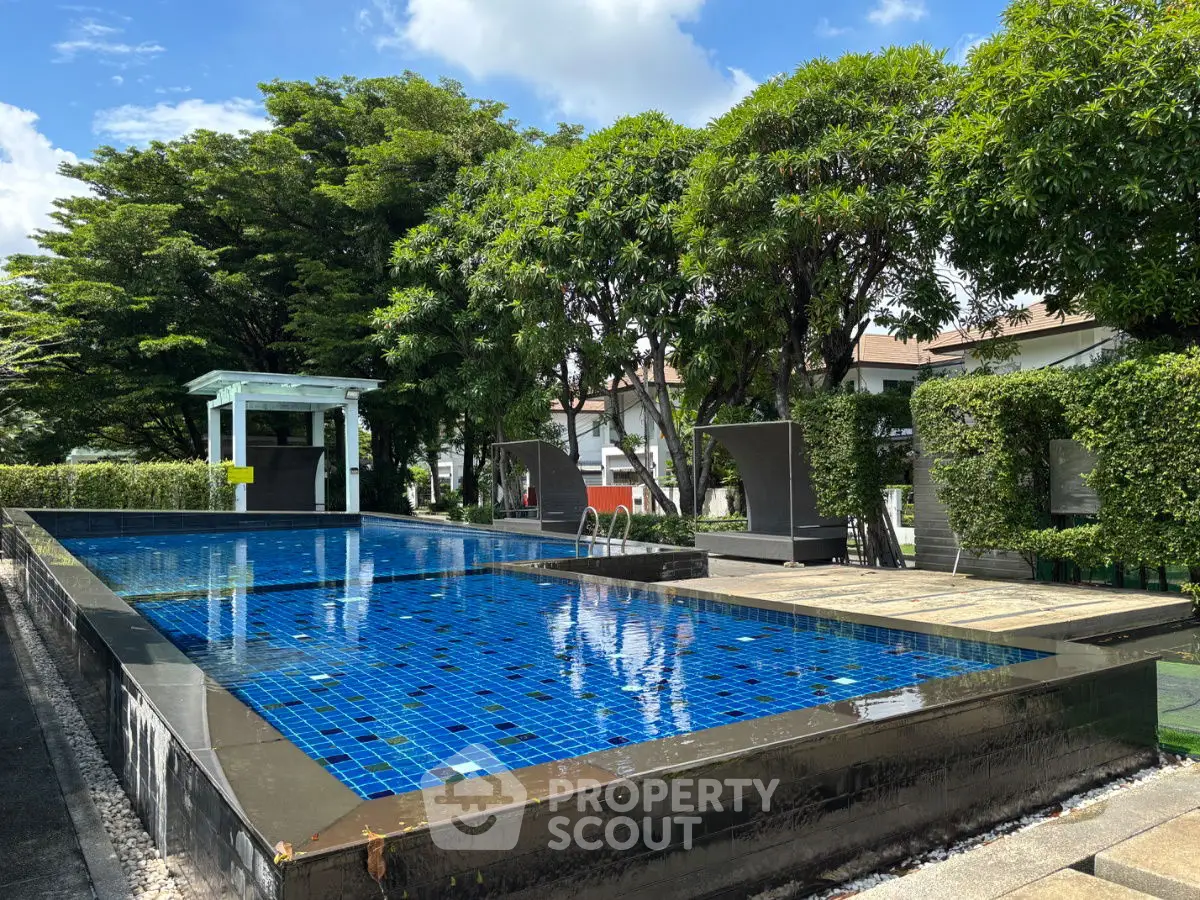 Luxurious outdoor pool area with lush greenery and modern lounge chairs, perfect for relaxation.