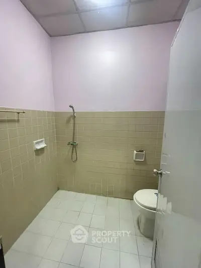 Simple bathroom with shower and toilet in a tiled setting
