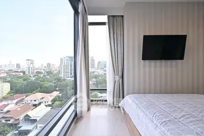 Modern bedroom with panoramic city view and wall-mounted TV