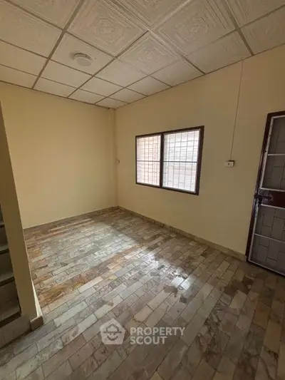 Spacious room with tiled flooring and large window, ideal for versatile use in a residential property.