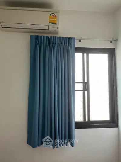 Minimalist room with blue curtains and air conditioning unit