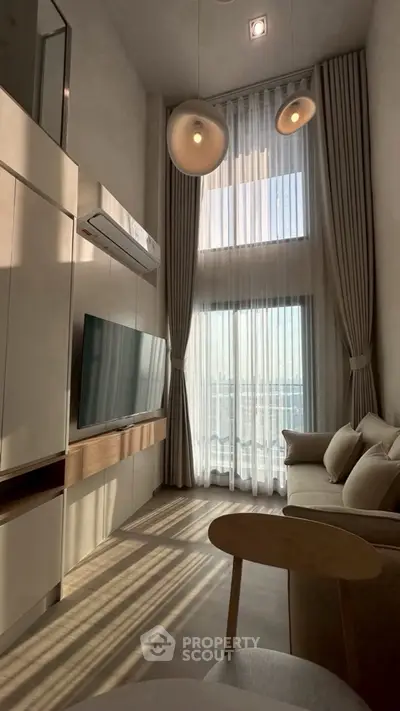 Modern living room with high ceilings and large windows offering abundant natural light.