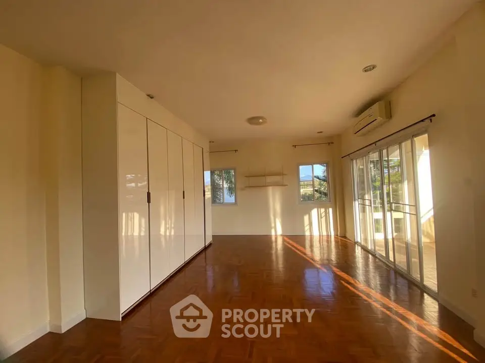 Spacious sunlit room with parquet flooring and large windows
