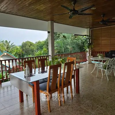 Spacious balcony with dining area and lush garden view, perfect for outdoor relaxation.
