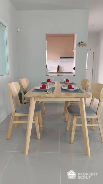 Modern dining area with wooden table and chairs, open view to stylish kitchen.