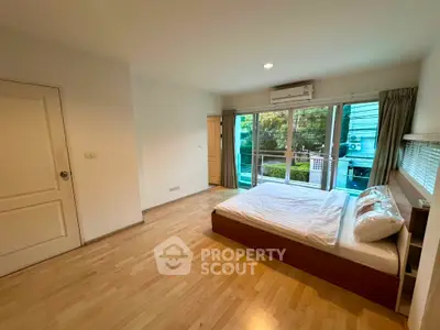 Spacious bedroom with balcony access and modern wooden flooring
