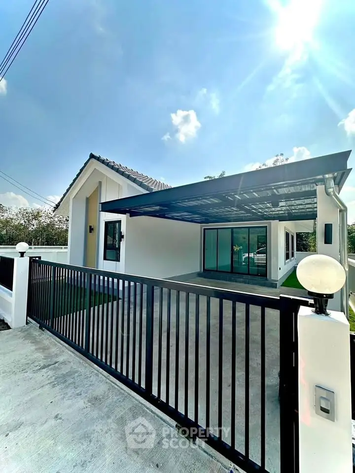 Modern single-story house with carport and sleek gate under a clear blue sky.