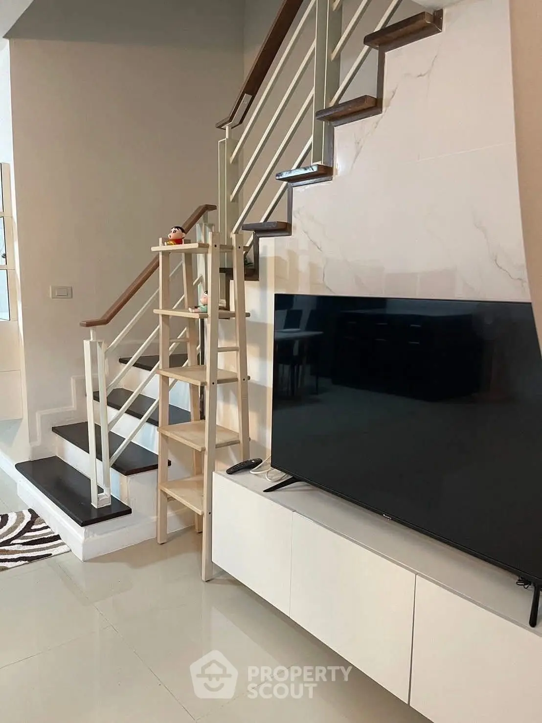 Modern living room with sleek staircase and large TV setup