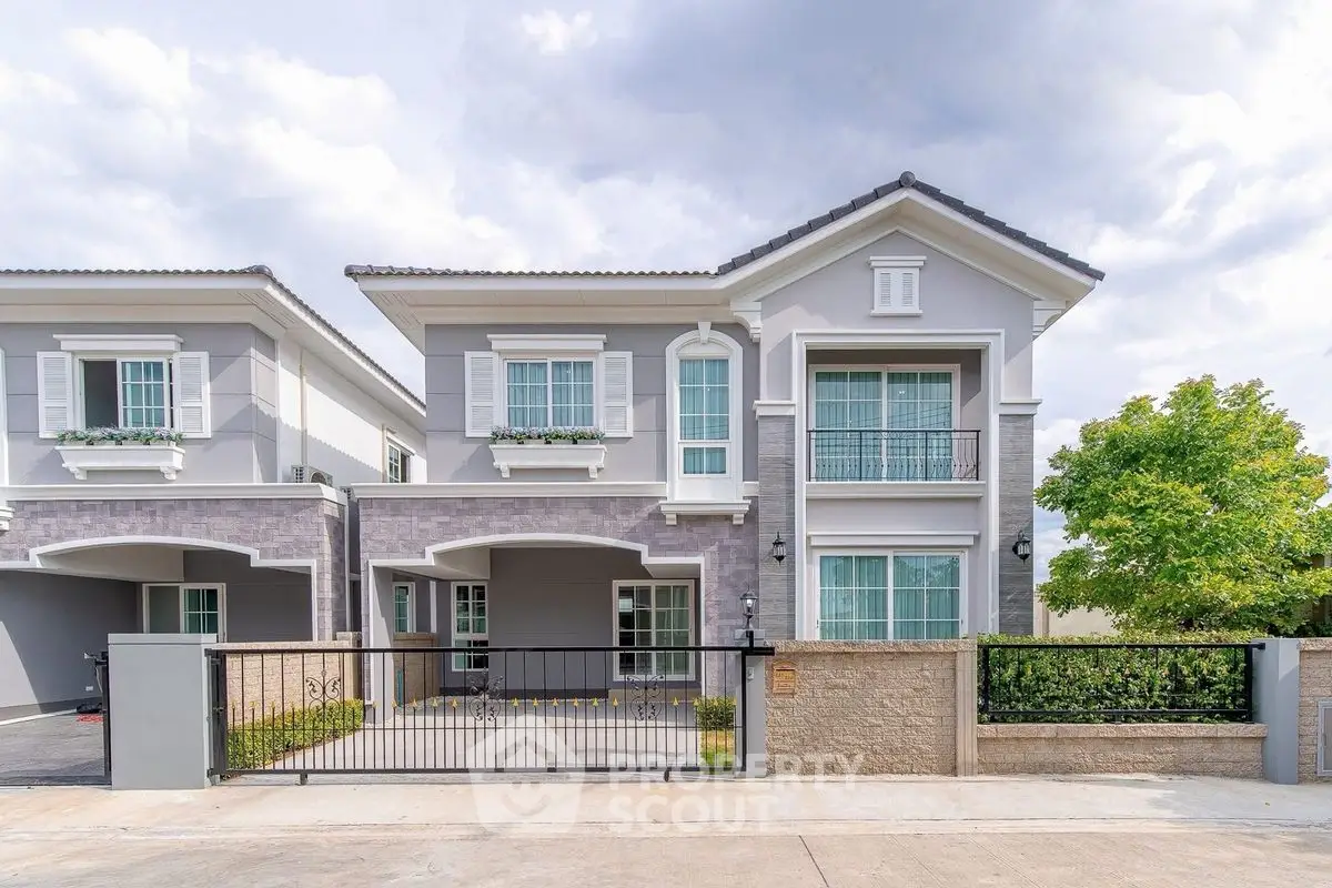 Elegant two-story house with modern facade and gated entrance in a serene neighborhood.