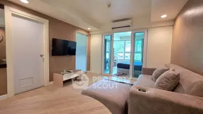 Modern living room with cozy sofa and wall-mounted TV, leading to a bright bedroom.