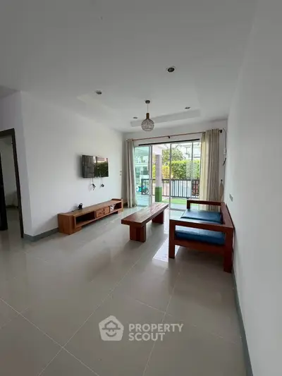 Spacious living room with modern furniture and large windows opening to a balcony with a view.