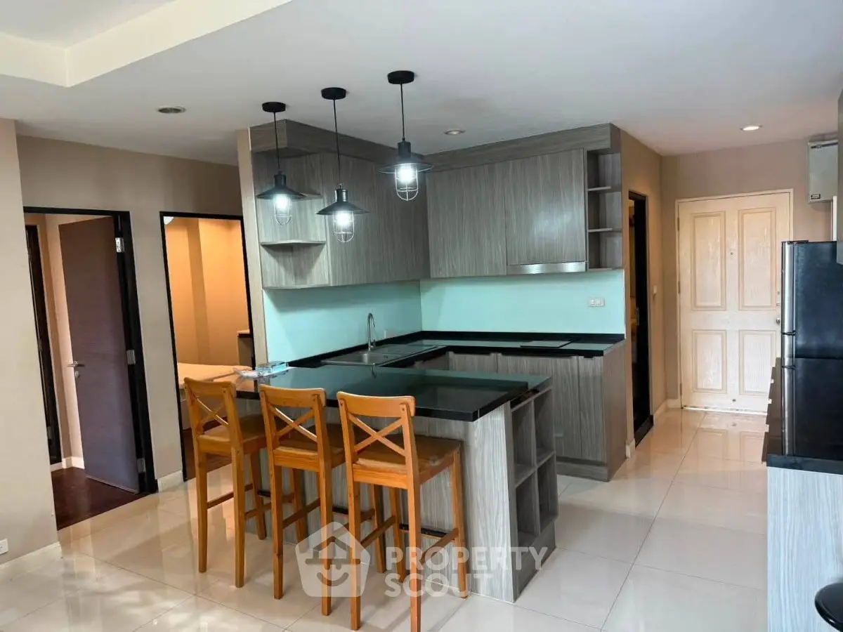Modern kitchen with island, wooden bar stools, and sleek cabinetry in a stylish apartment.