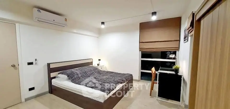 Modern bedroom with cozy bed, air conditioning, and stylish decor in a contemporary apartment.