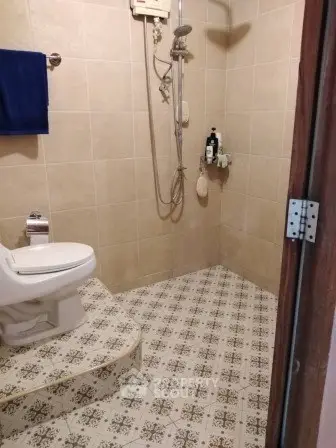 Cozy bathroom with tiled walls and floor, featuring a shower and toilet.