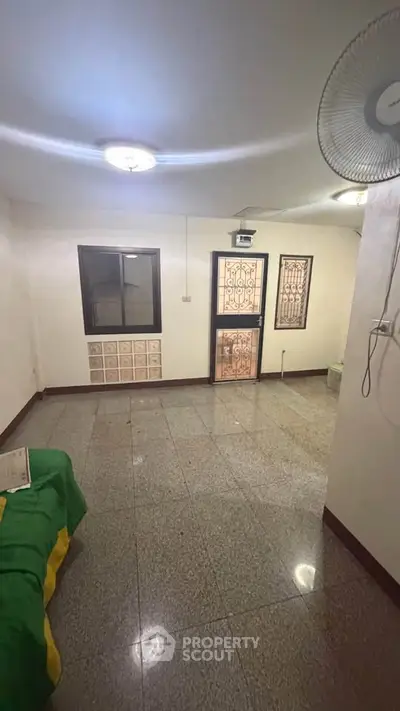 Spacious living room with tiled flooring and secure door, ideal for comfortable living.