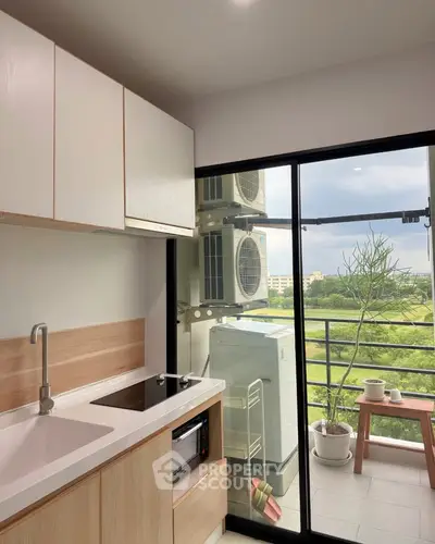 Modern kitchen with balcony view and sleek appliances in a high-rise apartment.