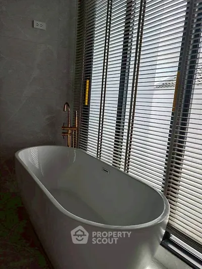 Luxurious bathroom with elegant freestanding bathtub and modern blinds.