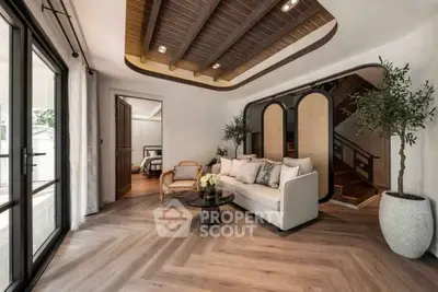 Luxurious living room with elegant decor and wooden ceiling beams, leading to a cozy bedroom.
