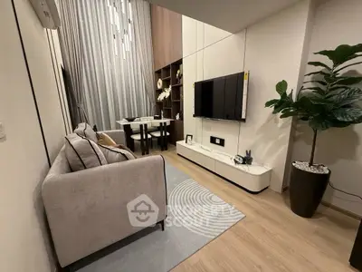 Modern living room with stylish decor and wall-mounted TV, featuring elegant lighting and cozy seating.