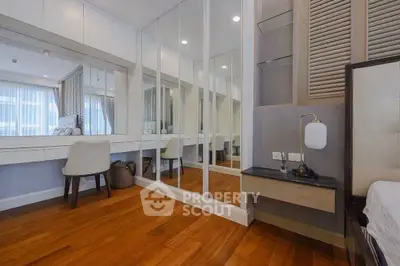 Elegant bedroom with mirrored wardrobe and wooden flooring in modern apartment