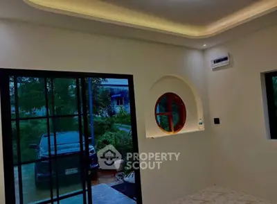 Modern living room with large glass doors and unique circular window design.