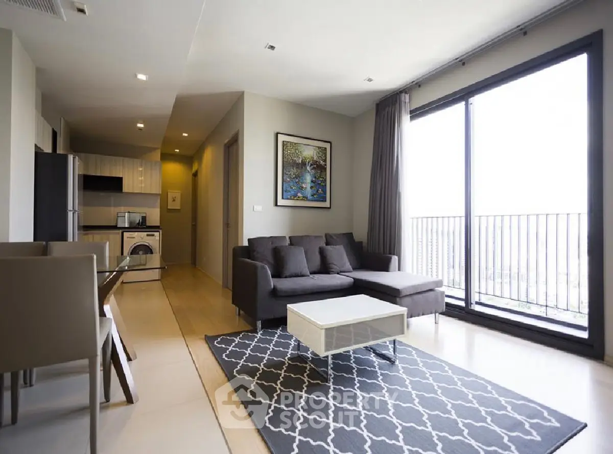 Modern living room with open kitchen, large window, and stylish decor in a high-rise apartment.
