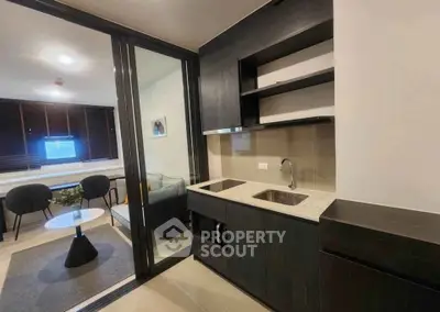 Modern kitchen with sleek dark cabinetry and open layout adjacent to cozy living area.