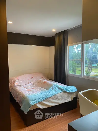 Cozy bedroom with large window and modern decor, perfect for relaxation.