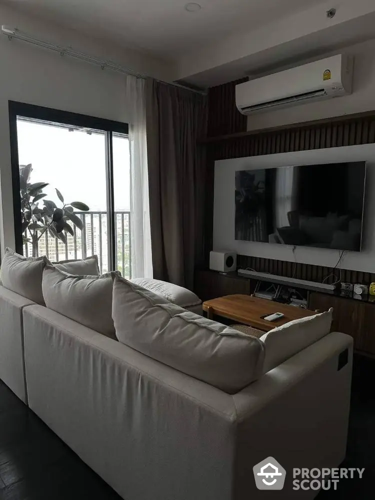 Elegantly designed living room with plush sofa, modern entertainment unit, and floor-to-ceiling window offering natural light.