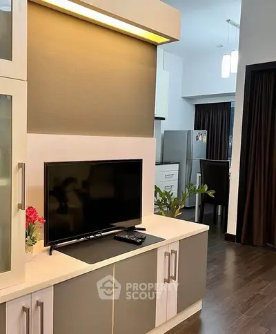 Modern living room with sleek TV setup and stylish kitchen view