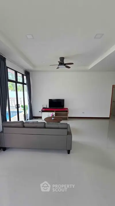 Spacious modern living room with sleek furniture and large windows offering natural light.