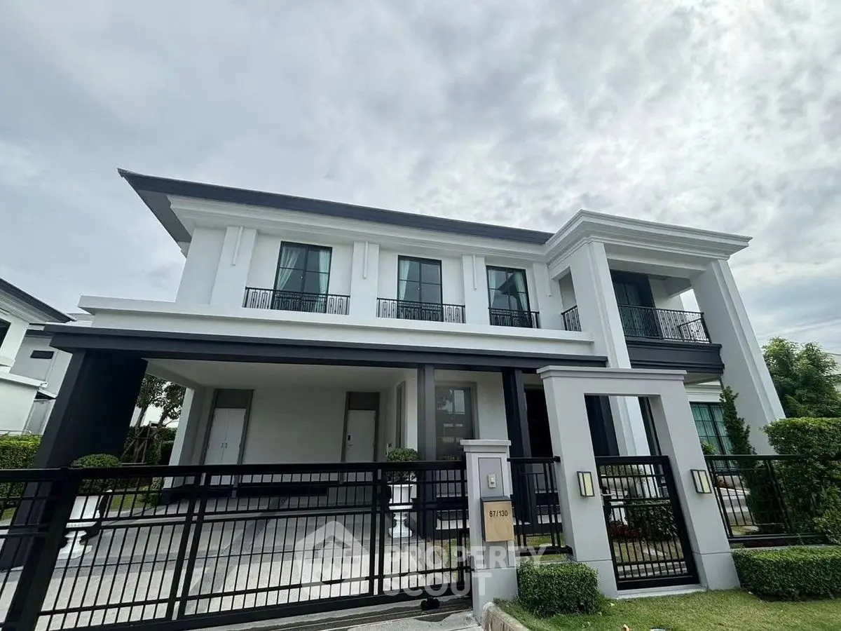 Elegant two-story modern house with gated entrance and manicured lawn.